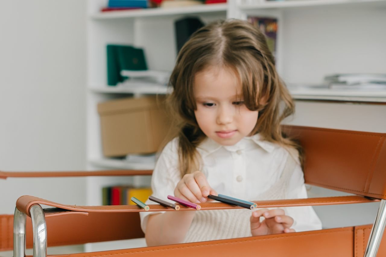 The Art of Drawing Readers In: Your attractive post title goes here A young caucasian girl arranging colored pencils indoors, focusing intently.